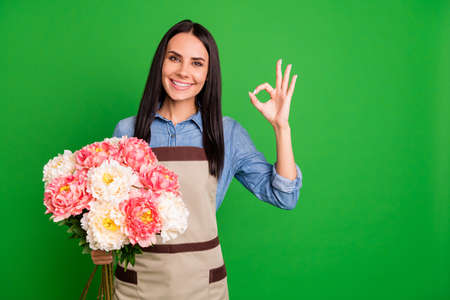 Portrait of charming lovely assistant vendor commercial option product natural botany self-employed person wear blue denim jean shirt long haircut positive isolated green backgroundの写真素材