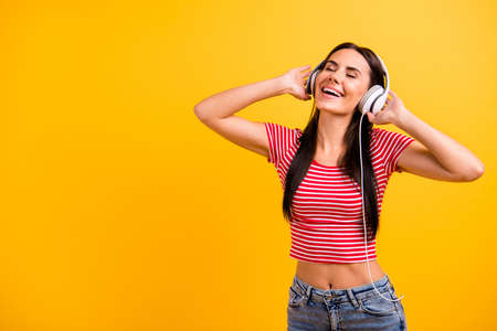 Portrait cute charming nice youth hear sound track favorite touch ear phones sing singer feel positive cheerful modern clothing weekend holiday vacation summer isolated yellow bright backgroundの写真素材