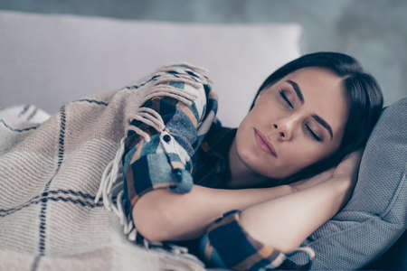 Close up side profile photo beautiful she her lady fell asleep hands arms under head eyes closed dreaming covered blanket wear checkered plaid shirt lying comfy divan flat house living room indoorsの写真素材