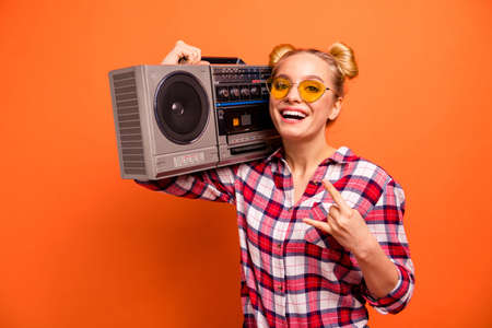 Close up photo beautiful nice she her nice lady toothy beaming smile vintage recorder shoulder hands arms horns symbol cool specs wear casual checkered plaid pink shirt isolated orange backgroundの写真素材