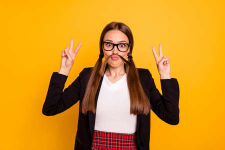 Portrait childish playful foolish fun funky funny youth free time make v-sign white red skirt pullover outfit black jacket blazer isolated yellow backgroundの写真素材