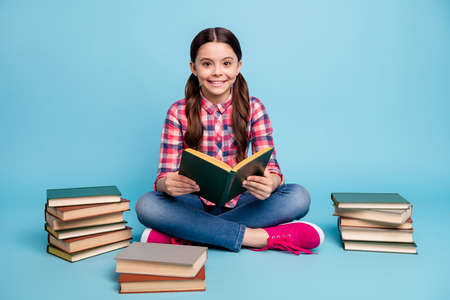 Portrait of nice attractive lovely intellectual cheerful girl nerd wearing checked shirt sitting in lotus pose library academic reading house isolated over bright vivid shine blue turquoise backgroundの写真素材