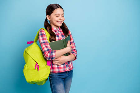 Portrait of nice attractive lovely cute cheerful cheery girl wearing checked shirt hugging materials library academic book isolated over bright vivid shine blue turquoise backgroundの写真素材