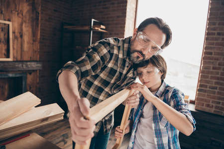 Close up photo of nice charming pretty people kid dad mentor teacher tutor show result masterclass smoothing handmade hobby diy checkered shirt brunet hair bearded indoors glasses goggles protectiveの写真素材