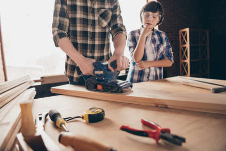 Cropped view of two nice creative person master handyman artisan dad fixing creating construction showing teaching son interesting occupation at modern studio loft industrial brick interiorの写真素材