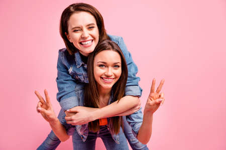 Close up photo two beautiful funky sisters she her best ladies party chill mood hugging v-sign symbol say hi hello piggyback posing wear jeans denim jackets blazers isolated bright pink backgroundの写真素材