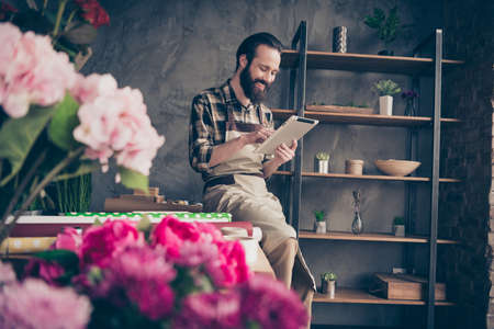 Portrait of his he nice attractive cheery cheerful glad guy gardener using digital e-book browsing at modern industrial loft concrete style indoors workplaceの写真素材