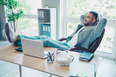 Close up side profile photo handsome he him his macho guy hands arms behind head napping resting overjoyed refreshment notebook table sit office chair wear formal wear jacket blazer jeans denimの写真素材