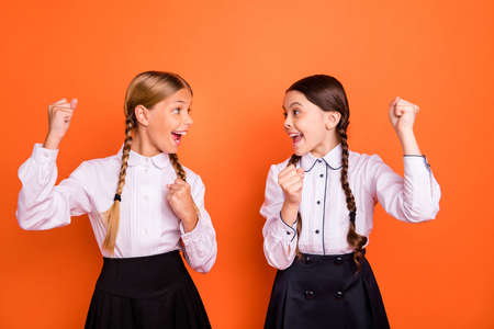 Portrait of two person nice attractive charming cute cheerful cheery ecstatic excited funny pre-teen girls good great news accomplishment isolated over bright vivid shine orange backgroundの写真素材