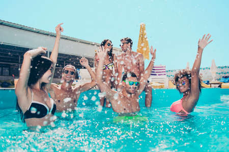 Photo of six friends hanging out in pool water enjoying best company raising hands up