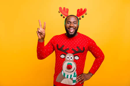 Portrait of his he nice attractive cheerful cheery positive funky optimistic guy wearing Santa look outfit style having fun showing v-sign isolated over bright vivid shine yellow backgroundの写真素材