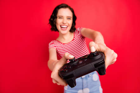 Close-up view of her she nice attractive lovely pretty cheerful cheery glad wavy-haired girl spending free time wireless game isolated over bright vivid shine red backgroundの写真素材