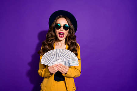 Portrait of her she nice-looking lovely chic gorgeous cheerful cheery glad positive rich wavy-haired lady holding in hands large sum salary isolated over bright vivid shine violet lilac backgroundの写真素材