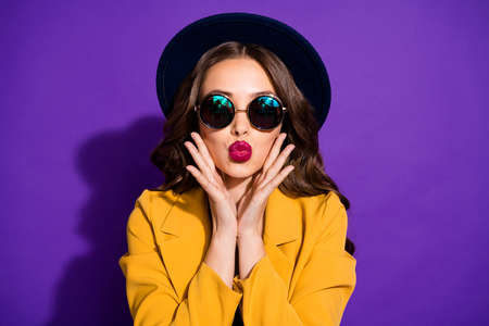 Photo of adorable lady sending air kisses wear specs yellow costume isolated purple backgroundの写真素材