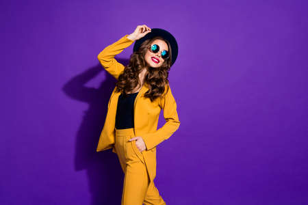 Photo of fashionable lady walking down street wear stylish hat yellow costume isolated purple backgroundの写真素材