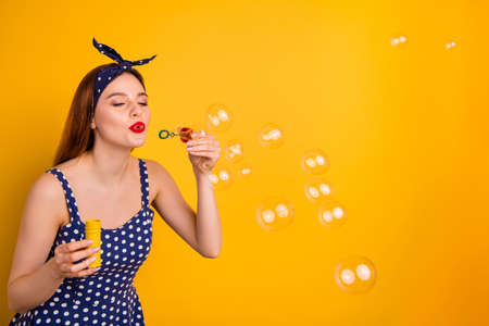 Portrait of charming youth have free time hold hand blow bubbles isolated over yellow background