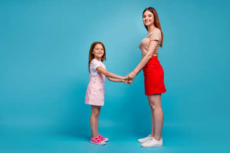 Photo of foxy little lady and mom holding hands standing opposite wear casual clothes isolated blue...