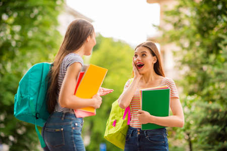 Back side photo of crazy girl with red hair holding note books hear news from her fellow having blue...