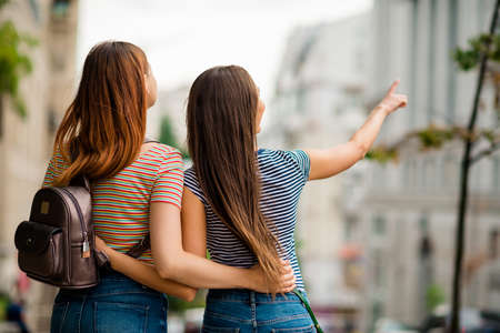 Back side photo of charming millennial wearing striped t-shirt denim jeans directing in town outsideの写真素材