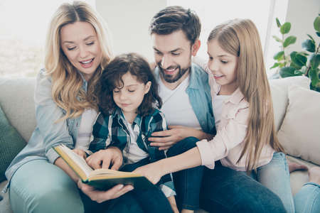 Young family two adopted children cozy sitting sofa listen mommy reading watch fairy tale drawings