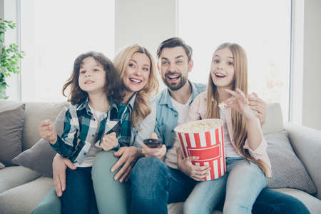 Photo of big family four members excited by watching tv show sit couch eat salty popcornの写真素材