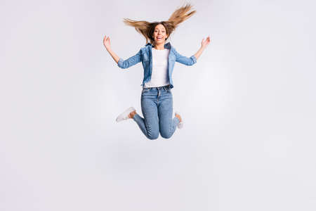 Full length body size photo of active energetic delightful with toothy beaming shiny smile lady jumping up isolated grey backgroundの写真素材