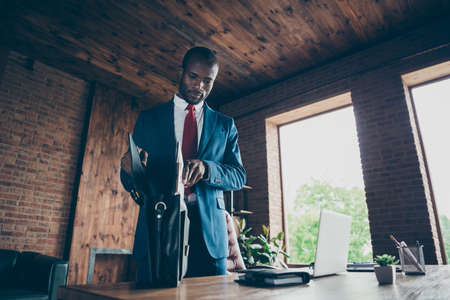 Photo of dark skin guy packing own documents papers into bag wear elegant costumeの写真素材