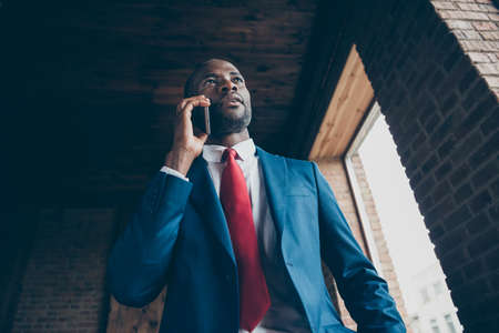 Low angle view photo of dark skin guy holding telephone hand speaking about important contract wear elegant costumeの写真素材