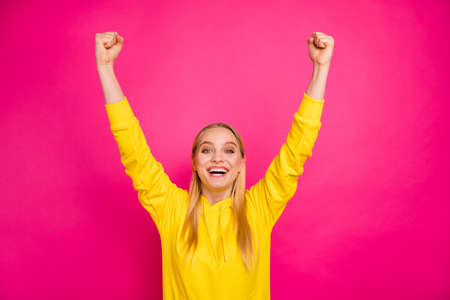 Photo of pretty yelling loud lady raising hands up wear yellow hoodie isolated pink backgroundの写真素材