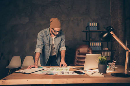 Photo of working at night time boss guy reading contract wear casual outfit stand near table in modern officeの写真素材