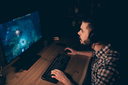 Close up side profile photo attentive professional he him his guy play videogame tournament chat communicate talk teammates headset wear casual plaid checkered shirt internet cafe house indoorsの写真素材