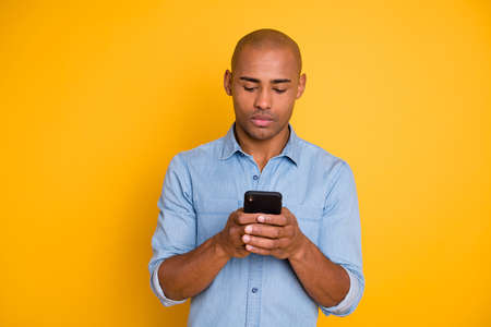 Portrait of focused handsome youth hod hand modern technology search information isolated over yellow backgroundの写真素材