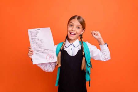 Portrait of nice attractive charming cute smart clever cheerful cheery successful glad pre-teen girl demonstrating great cool best grade having fun isolated on bright vivid shine orange backgroundの写真素材