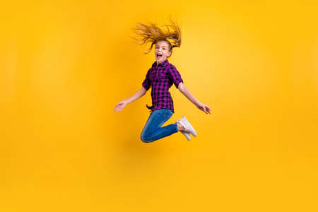 Full size side photo of small pupil jump high hooray holidays wear casual checkered shirt jeans denim isolated yellow backgroundの写真素材
