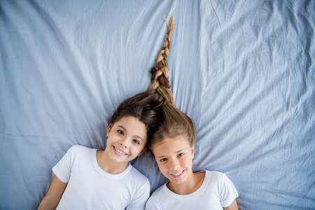 Top high angle photo of charming children feel content glad lie bed room bedroom indoorsの写真素材