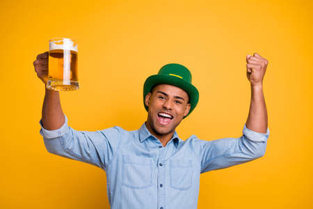 Close up photo of dark skin guy hold hands raise beer glass irish traditional hat pub wear jeans...