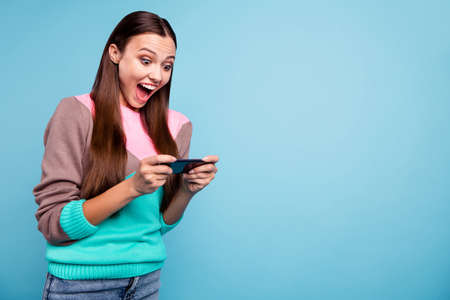 Photo of positive screaming playful lady using telephone for enjoying new digital game isolated...