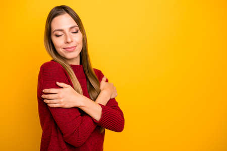 Closeup photo of pretty lady holding shoulders close eyes wear burgundy pullover isolated bright yellow backgroundの写真素材
