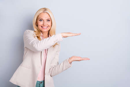 Portrait of her she nice-looking attractive lovely confident cheerful cheery gray-haired lady showing copy space invisible ad advert isolated over light white gray pastel backgroundの写真素材