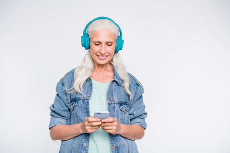 Portrait of charming person with headset on head looking device hearing melodies wearing jeans isolated over white backgroundの写真素材