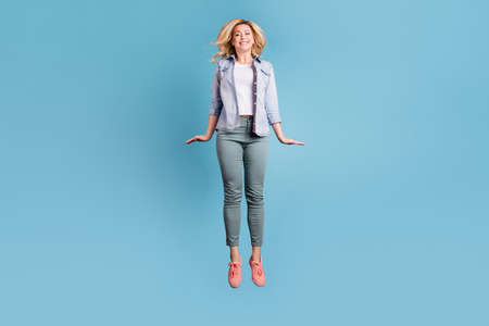 Full body photo of attractive pretty lady jumping with beaming toothy smile isolated over blue...