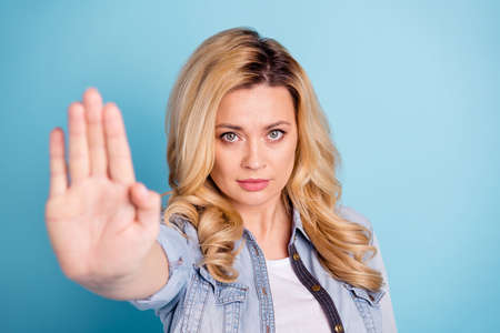 Close up photo of strict raising palm looking at camera isolated over blue backgroundの写真素材