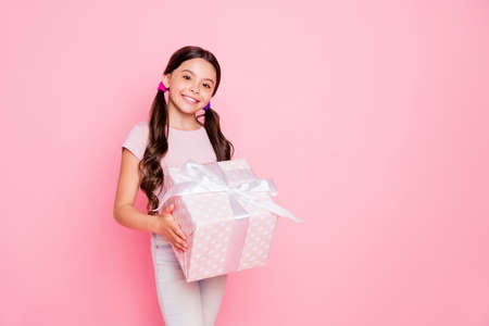 Portrait of pretty girl holding giftbox looking dressed white pants trousers isolated over pink backgroundの写真素材