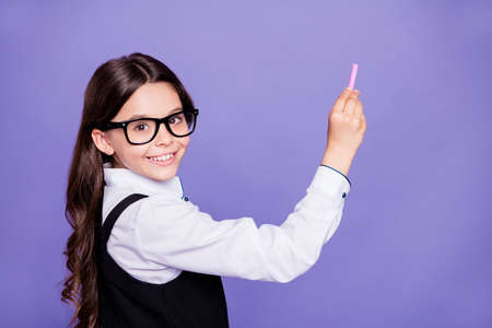 Close-up portrait of nice attractive smart clever intellectual diligent cheerful wavy-haired pre-teen girl writing example copy space class work isolated over bright vivid shine violet backgroundの写真素材