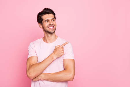 Portrait of his he nice attractive cheerful cheery confident content dreamy guy pointing forefinger aside promotion cool good surprise gift present ad isolated over pink pastel backgroundの写真素材
