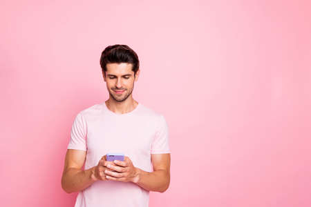 Portrait of his he nice attractive lovely concentrated focused guy reading news notification using fast speed device isolated over pink pastel backgroundの写真素材