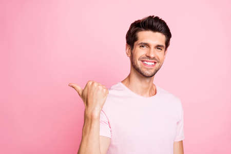 Close-up portrait of his he nice attractive lovely cheerful cheery glad content guy pointing aside ad advert copy space decision isolated over pink pastel backgroundの写真素材