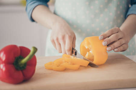 Cropped closeup photo of neat arms wife cut pepper wear dotted apron making diet dishes for familyの写真素材