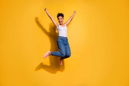 Photo of a happy dark skin lady wearing casual jeans denim pants and tank-top isolated bright yellow backgroundの写真素材