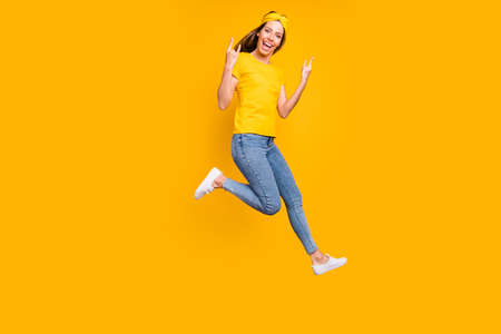 Full body photo of beautiful lady jumping high rejoicing at metal concert wear casual clothes isolated yellow backgroundの写真素材